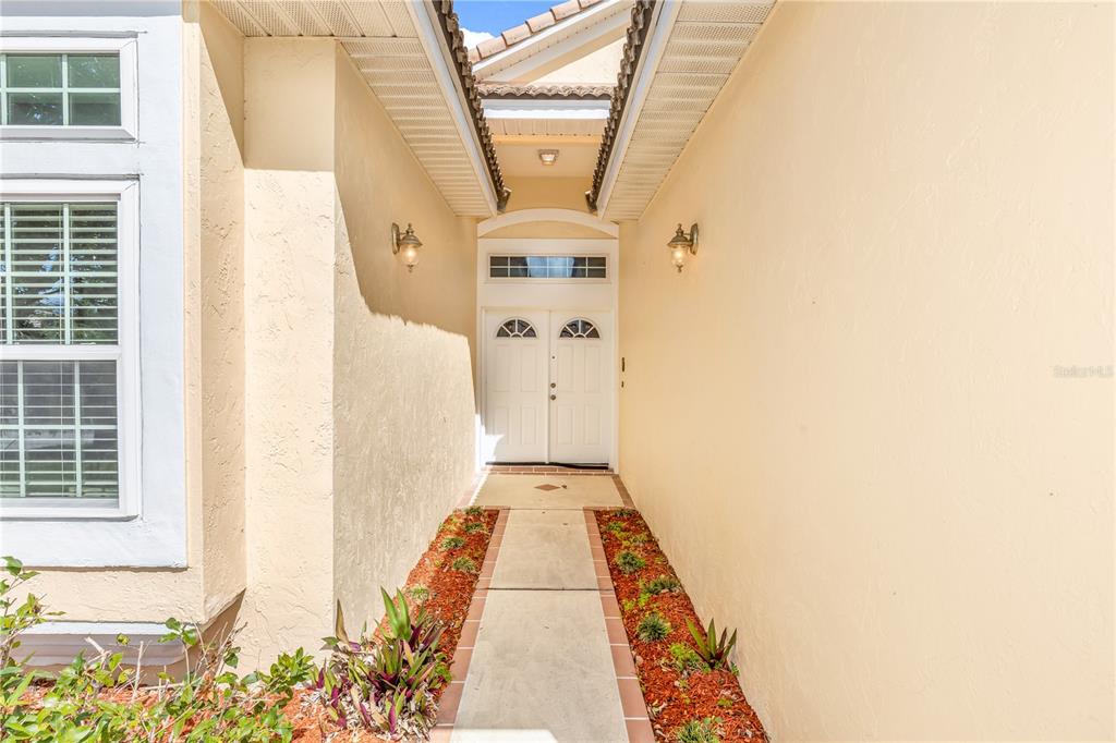 A concrete walkway leads to a double front door recessed between two beige exterior walls — 414 FAIRLANE DRIVE, DEBARY, FL