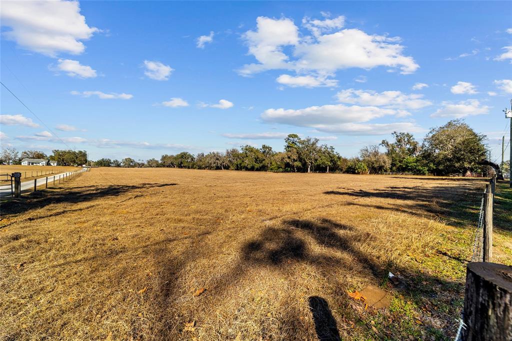 A wide, dry, grassy field is enclosed by a wire fence under a blue sky — 4101 SE 110TH STREET, BELLEVIEW, FL
