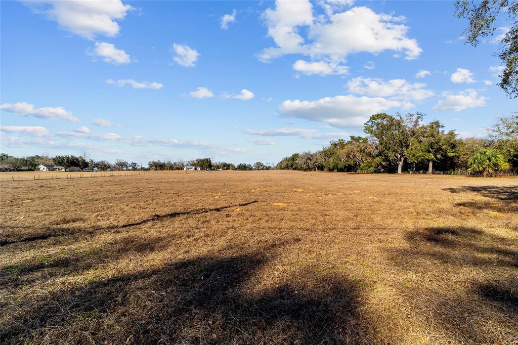 A large, flat, dry grassy field under a blue sky with scattered clouds — 4101 SE 110TH STREET, BELLEVIEW, FL