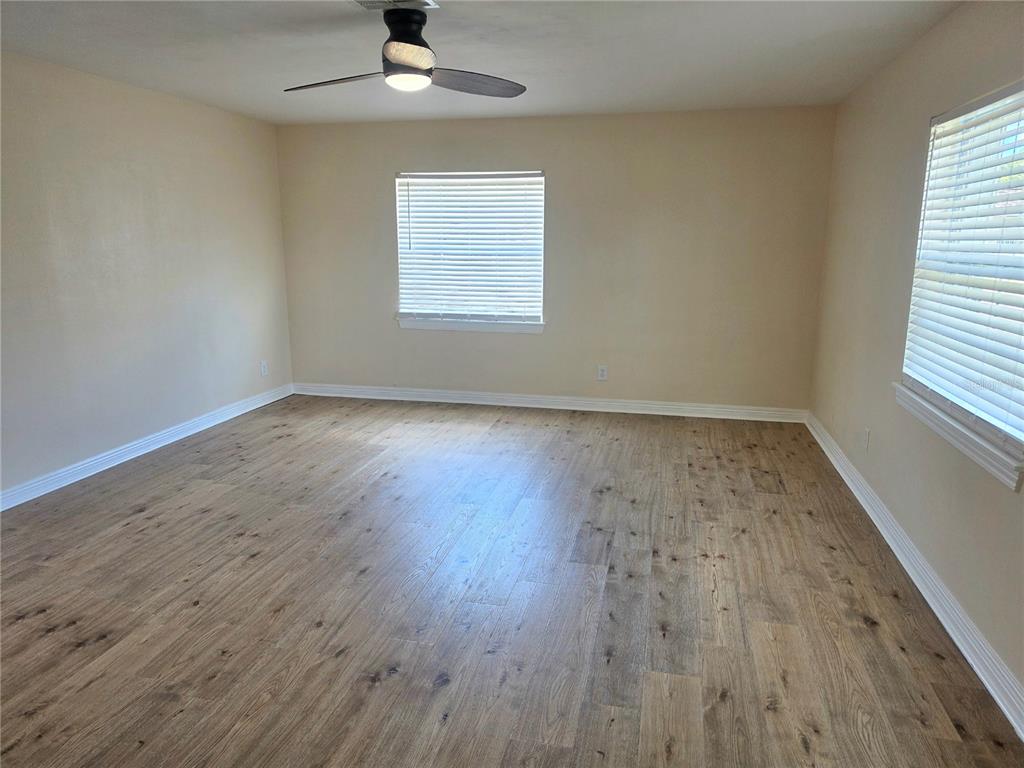 An empty bedroom features light-colored walls, wood-look flooring, two windows with blinds, and a ceiling fan — 100 ALACHUA DRIVE, WINTER HAVEN, FL