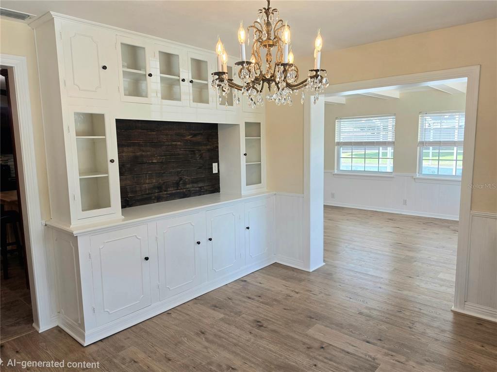 A dining room features white built-in cabinetry with a dark wood backsplash and a crystal chandelier — 100 ALACHUA DRIVE, WINTER HAVEN, FL