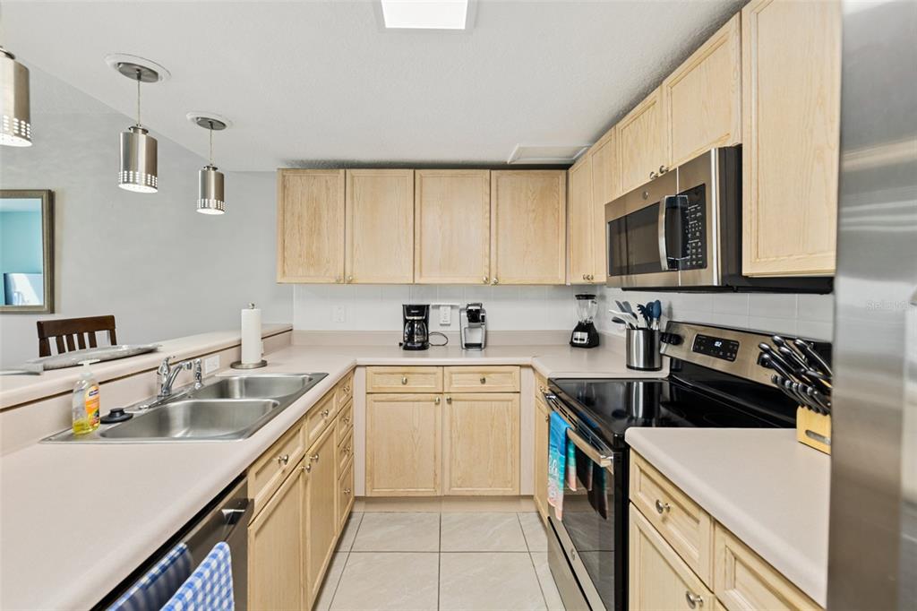 A kitchen features light wood cabinets, laminate countertops, stainless steel appliances, and tile flooring — 5300 S ATLANTIC AVENUE UNIT 1-505, NEW SMYRNA BEACH, FL