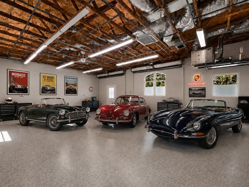 A garage with a speckled floor, exposed ceiling, and three classic vintage sports cars — 7311 PROCTOR ROAD, SARASOTA, FL