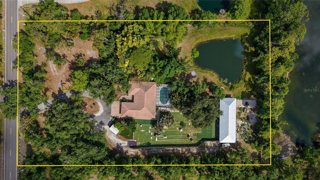 An aerial view shows a house with a pool, a pond, and a sports court — 7311 PROCTOR ROAD, SARASOTA, FL