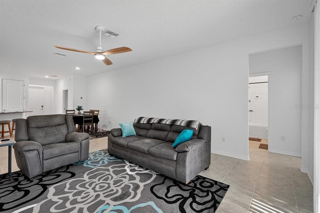 A living room features a gray sofa, a matching armchair, and a patterned area rug — 2607 HOPTREE LANE, EDGEWATER, FL