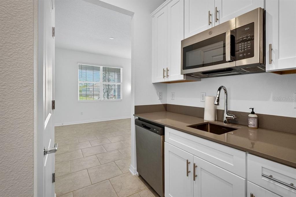 A kitchen features white cabinets, stainless steel appliances, and a brown countertop — 2607 HOPTREE LANE, EDGEWATER, FL
