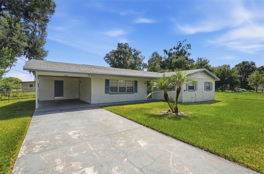 A single-story brick house with a carport, a concrete driveway, and a front lawn — 1704 WAYMAN STREET, LAKELAND, FL