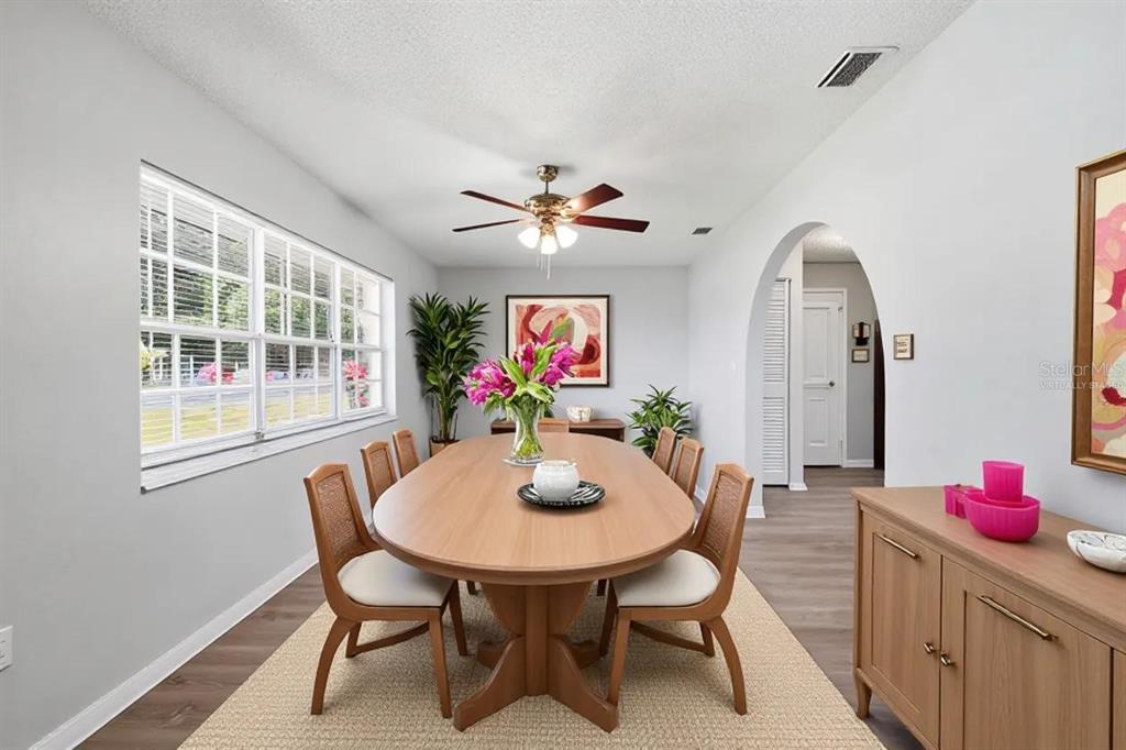 A dining room with an oval wooden table, six chairs, and an arched doorway — 1704 WAYMAN STREET, LAKELAND, FL