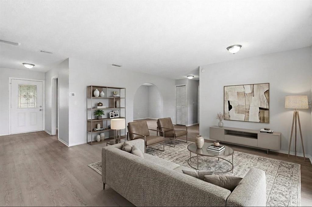 A living room features light wood-look flooring, a gray sofa, two leather chairs, and a rug — 1704 WAYMAN STREET, LAKELAND, FL