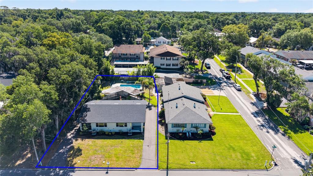 An aerial view shows two adjacent residential buildings with driveways, lawns, and a backyard pool — 1012 N BAKER STREET, MOUNT DORA, FL