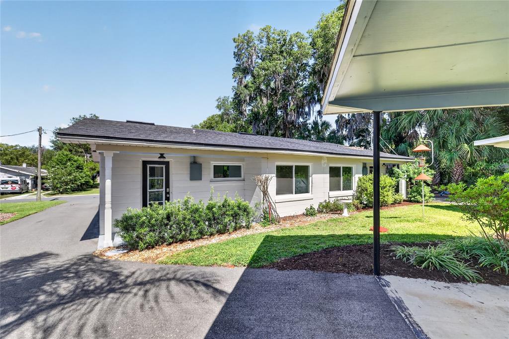 A single-story house exterior features a driveway, a carport, and a landscaped front yard — 1012 N BAKER STREET, MOUNT DORA, FL