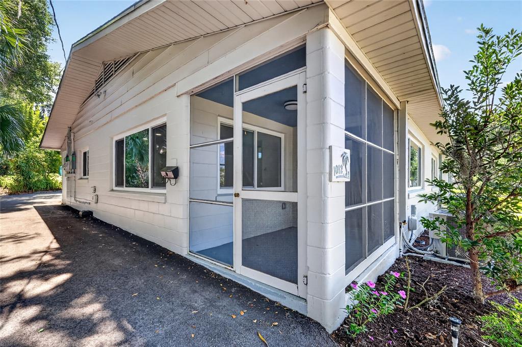 A white concrete block building features a screened-in porch and a paved driveway — 1012 N BAKER STREET, MOUNT DORA, FL