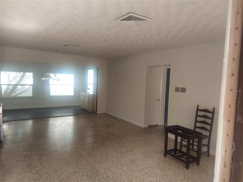 An interior view of a room with speckled flooring, a textured ceiling, and an adjacent sunroom — 2695 S EAST AVENUE, SARASOTA, FL