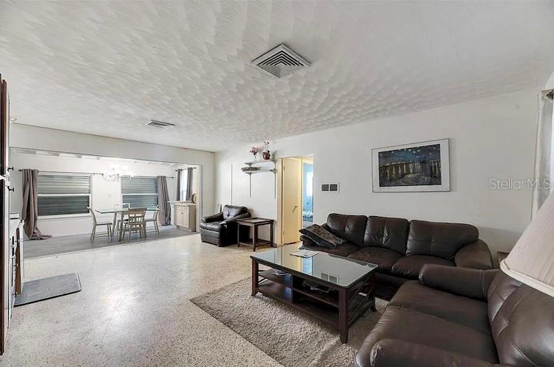 A living room with a textured ceiling, tile flooring, and a dark leather sofa set — 2695 S EAST AVENUE, SARASOTA, FL