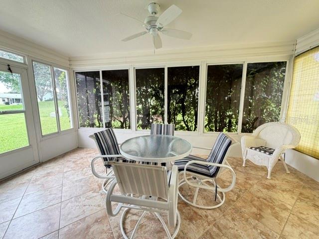 A sunroom features a glass-topped table, four chairs, a wicker chair, and a ceiling fan — 335 SAN MARINO DRIVE, LADY LAKE, FL
