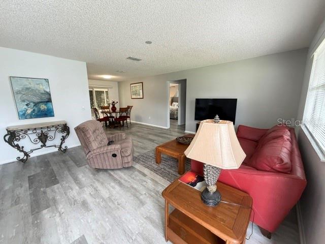 A living room features a red sofa, a recliner, and a dining area in the background — 335 SAN MARINO DRIVE, LADY LAKE, FL