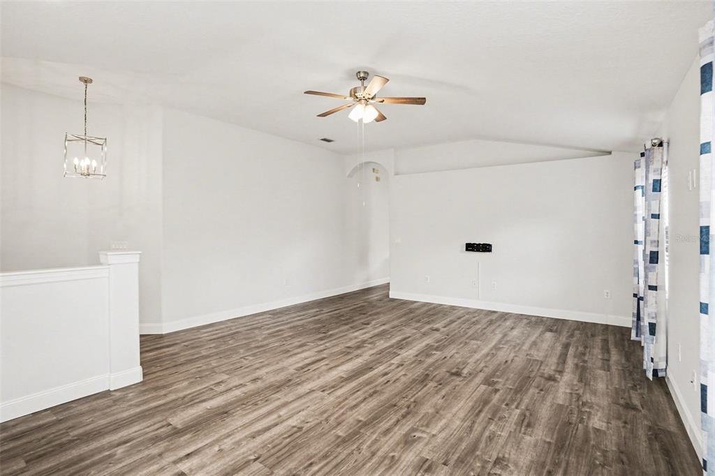 An empty living room features wood-look flooring, a ceiling fan, and a white vaulted ceiling — 9524 ROLLING CIRCLE, SAN ANTONIO, FL