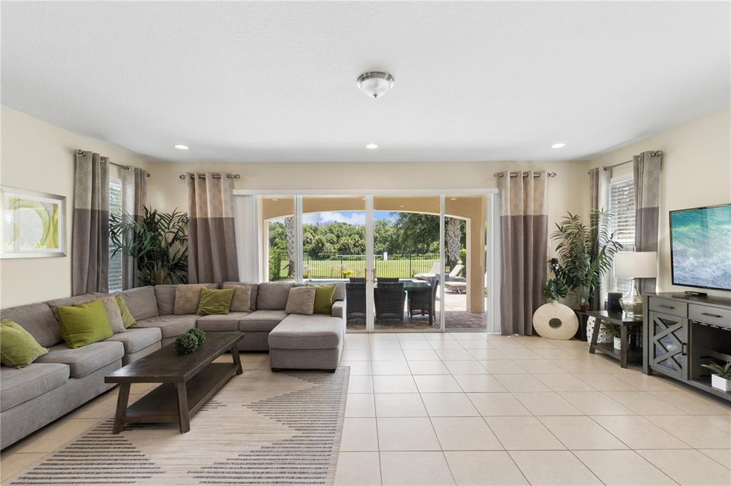 A living room features a large sectional sofa, a coffee table, and sliding glass doors — 785 DESERT MOUNTAIN COURT, KISSIMMEE, FL