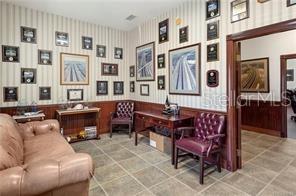 A home office features a leather sofa, a wooden desk, and walls decorated with framed awards — 62 HIGHWAY 40 W, INGLIS, FL