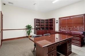 An office features a large wooden desk, built-in shelving, and a window with blinds — 62 HIGHWAY 40 W, INGLIS, FL