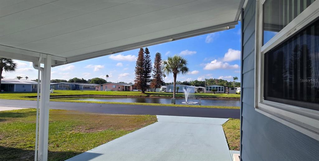 A view from a covered porch overlooking a pond with a fountain and neighboring homes — 86 PARSON DRIVE, WINTER HAVEN, FL