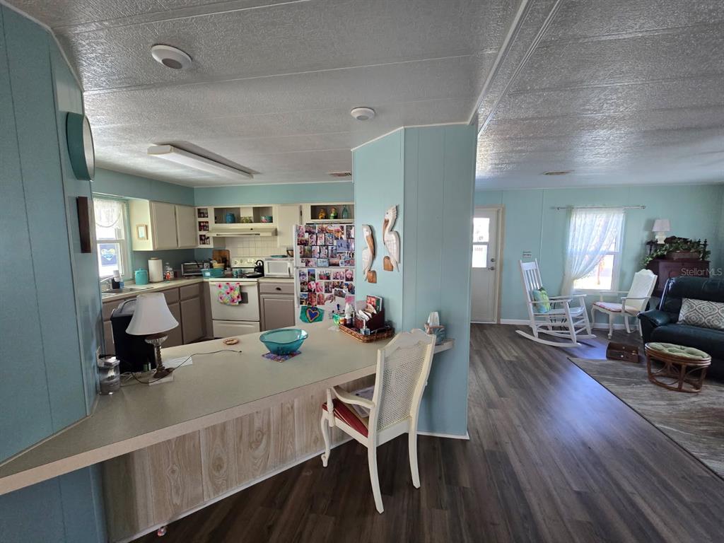 An open-concept kitchen and living area feature light blue walls, wood-look flooring, and a peninsula — 86 PARSON DRIVE, WINTER HAVEN, FL