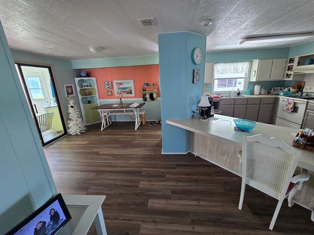 An open-concept kitchen and dining area with light blue walls, wood-look flooring, and white cabinetry — 86 PARSON DRIVE, WINTER HAVEN, FL