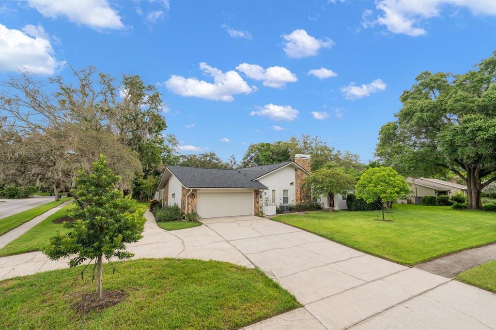 A single-story house with a stone chimney, a two-car garage, and a concrete driveway — 2423 FOXHEAD WAY, CLEARWATER, FL