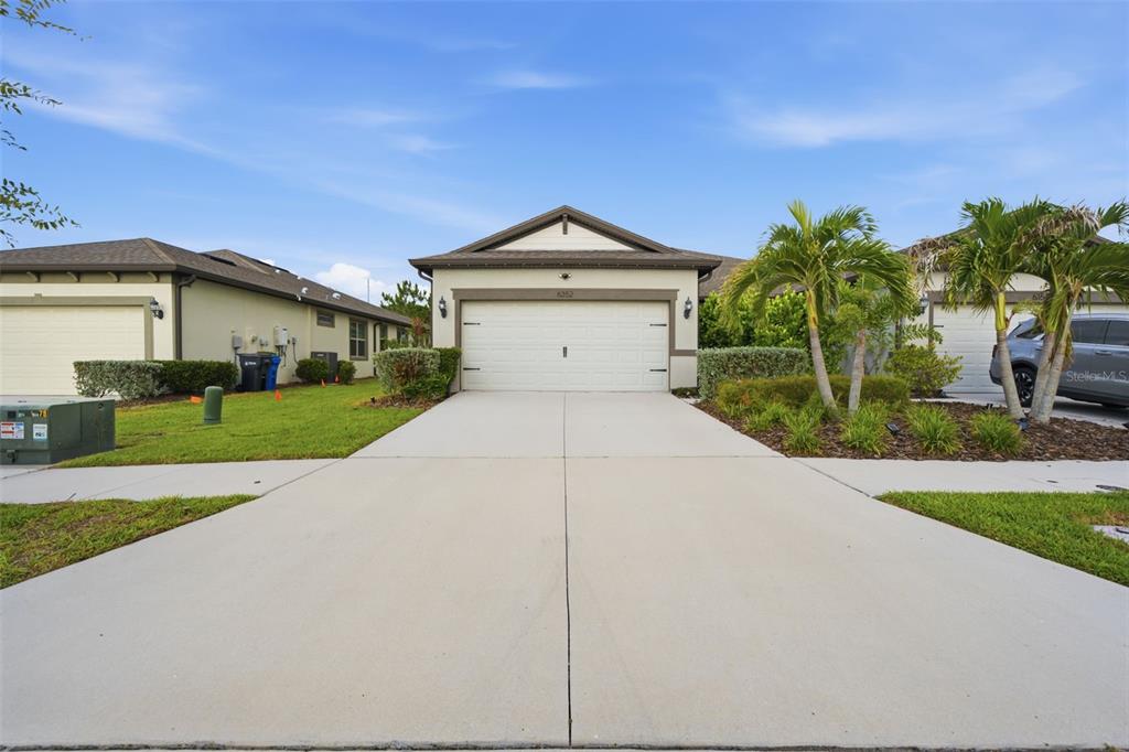 A single-story house with a white garage door, concrete driveway, and palm trees — 6352 MOORING LINE CIRCLE, APOLLO BEACH, FL