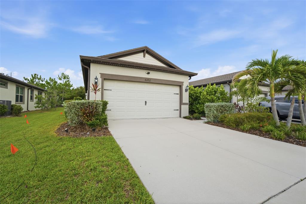 A single-story house with a white garage door, beige siding, and a concrete driveway — 6352 MOORING LINE CIRCLE, APOLLO BEACH, FL