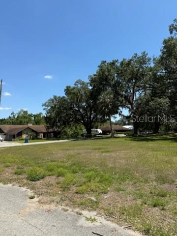 A grassy, vacant lot sits in the foreground with mature trees and houses in the background — 0 RIVER OAK DRIVE, FORT MEADE, FL