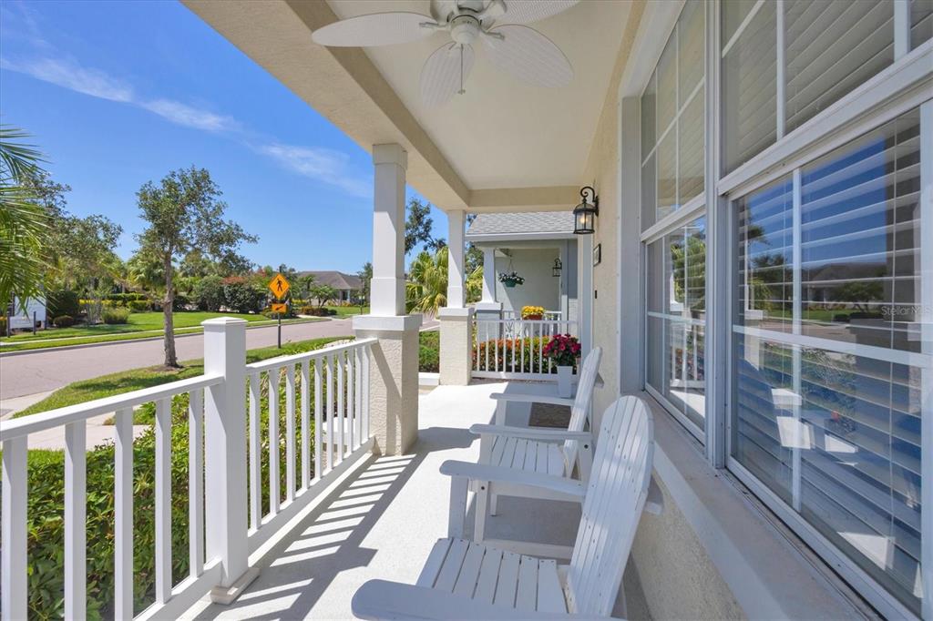 A covered front porch features white railings, two white chairs, and a ceiling fan — 4811 WOODBROOK DRIVE, SARASOTA, FL