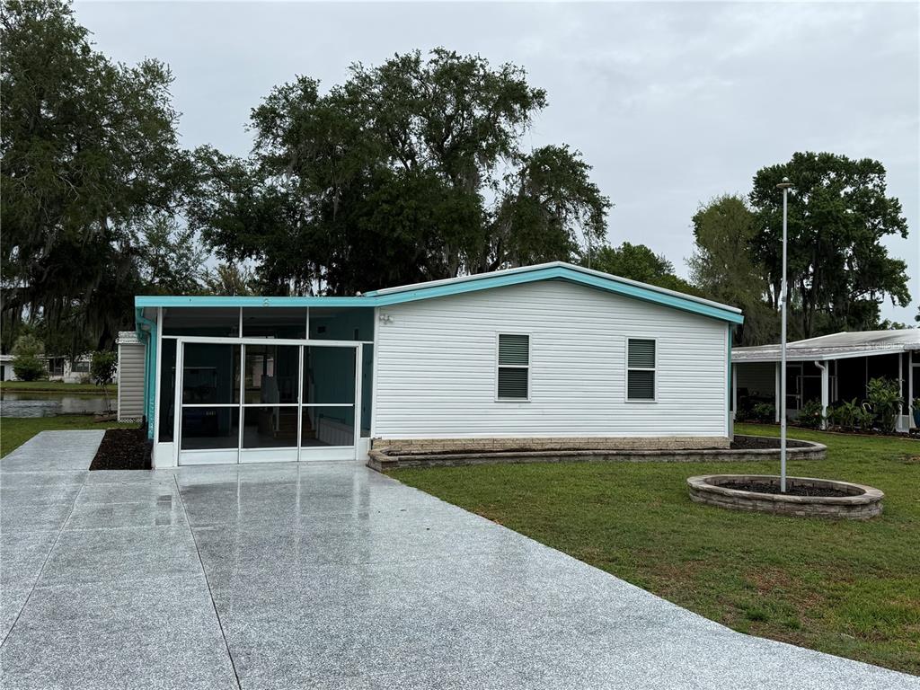 A single-story mobile home with white siding, a screened-in porch, and a paved driveway — 8 ROBIN ROAD, WILDWOOD, FL