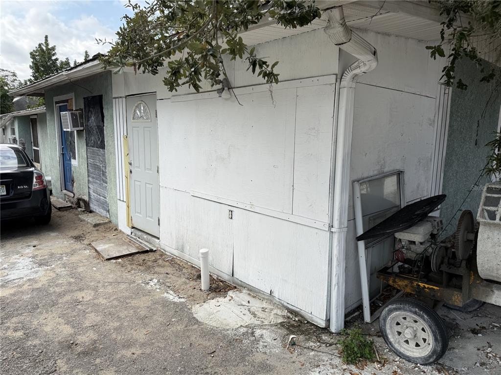 An exterior view of a building with a white plywood wall, a door, and equipment — 310 E BOOKER STREET, AVON PARK, FL