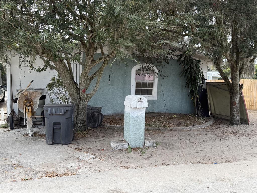 A light blue house exterior features a mailbox, a concrete mixer, and large trees — 310 E BOOKER STREET, AVON PARK, FL