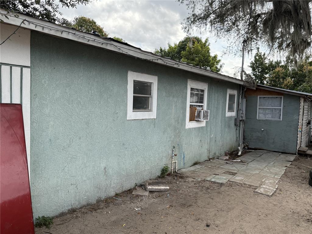 The exterior of a house with stucco walls, several windows, and a paved patio area — 310 E BOOKER STREET, AVON PARK, FL