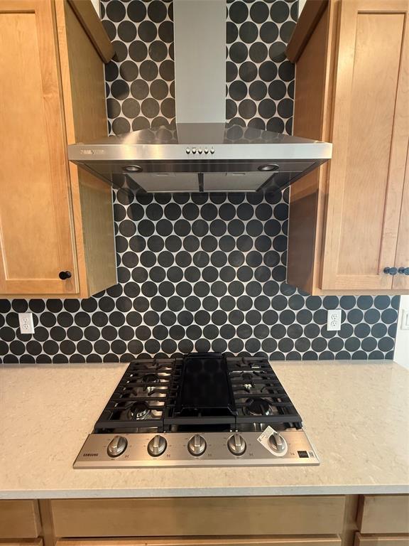 A kitchen features a stainless steel gas cooktop, range hood, and dark circular tile backsplash — 5123 BUTTONSAGE DRIVE, ST CLOUD, FL