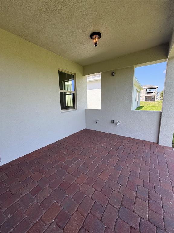 A covered patio features red brick pavers, a ceiling light, and views of a neighboring house — 5123 BUTTONSAGE DRIVE, ST CLOUD, FL