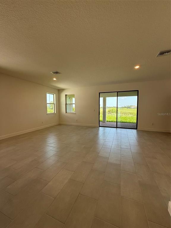 An empty room features light-colored tile flooring, white walls, recessed lighting, and sliding glass doors — 5123 BUTTONSAGE DRIVE, ST CLOUD, FL