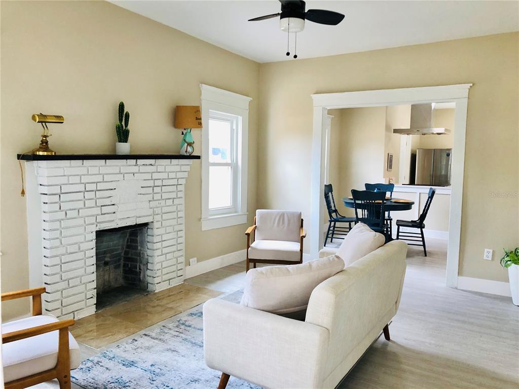 A living room features a white brick fireplace, light wood flooring, and an adjacent dining area — 908 VINE AVENUE, CLEARWATER, FL