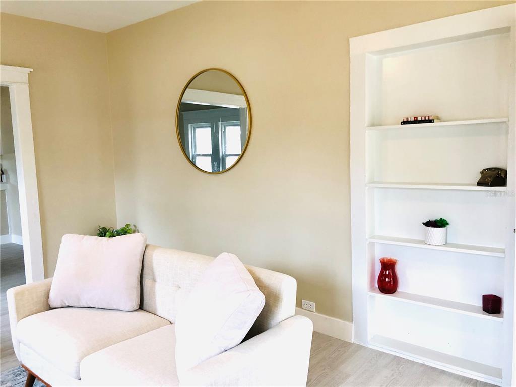 A living room features a light-colored sofa, a round gold-framed mirror, and built-in white shelving — 908 VINE AVENUE, CLEARWATER, FL