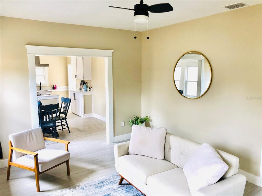 A living room with a sofa, armchair, and a doorway leading into a kitchen — 908 VINE AVENUE, CLEARWATER, FL