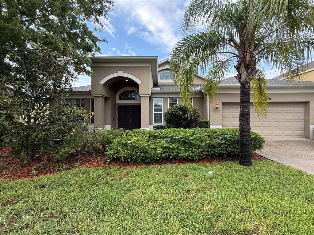 A tan single-story house with a palm tree, a two-car garage, and a landscaped front yard — 10856 BREAKING ROCKS DRIVE, TAMPA, FL