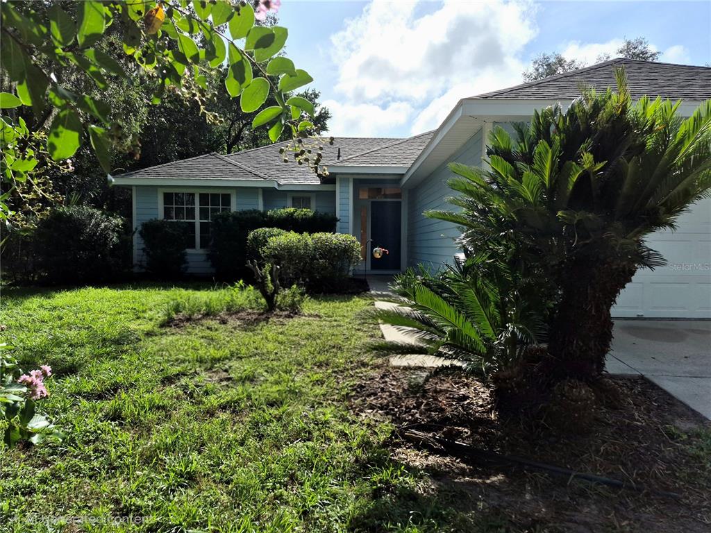 A light blue house with a front lawn, a palm tree, and a garage — 4341 NW 34TH TERRACE, GAINESVILLE, FL