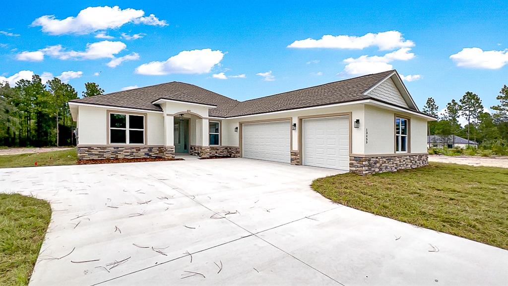 A single-story house with a stone-accented facade, two-car garage, and a concrete driveway — 12276 SW 98TH STREET, DUNNELLON, FL