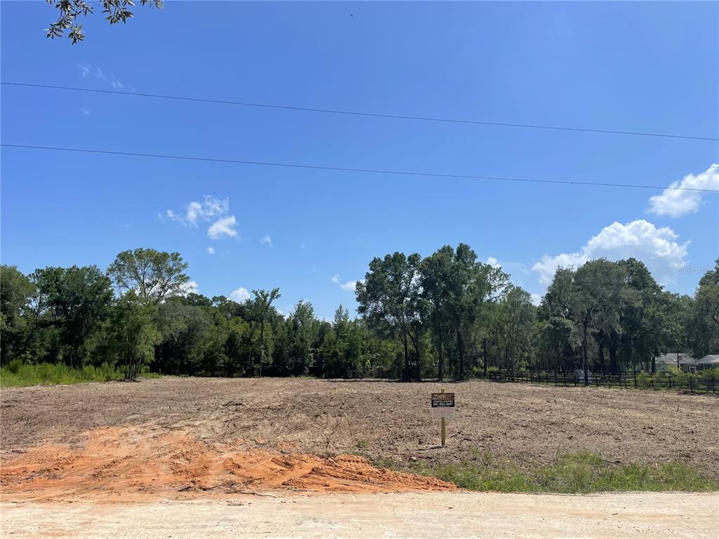A cleared, vacant lot with a small sign stands before a line of mature trees — 12276 SW 98TH STREET, DUNNELLON, FL