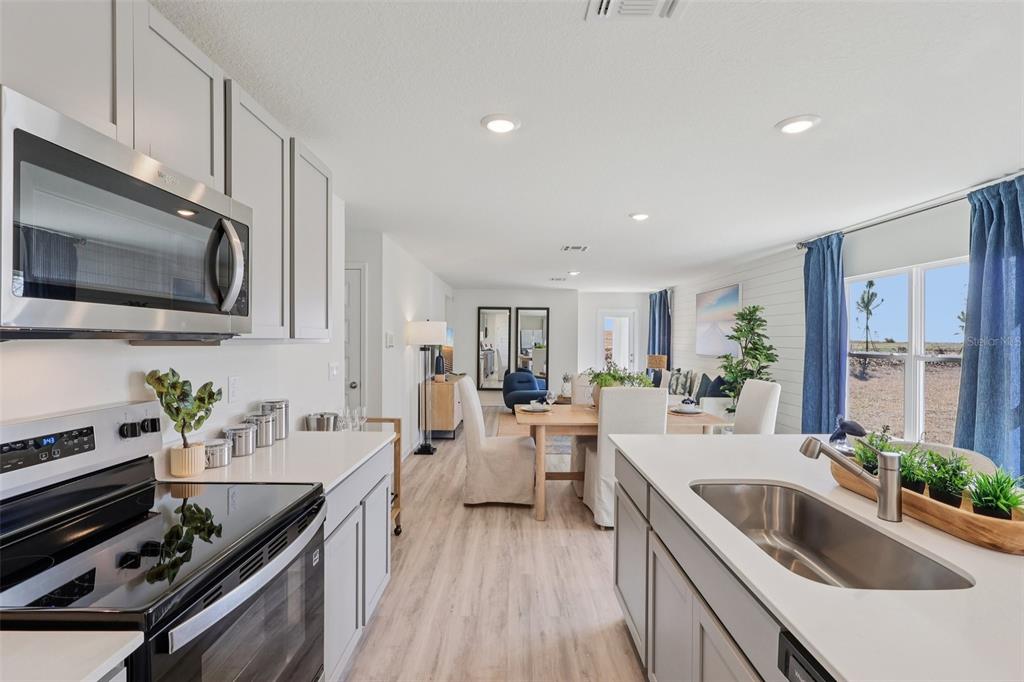 A kitchen with light gray cabinets and white countertops overlooks a dining and living area — 1522 LAS PALMAS STREET, LAKELAND, FL