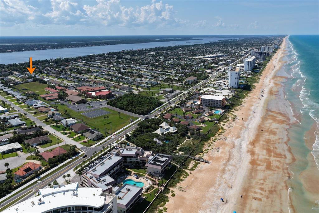 An aerial view shows a coastal town with a beach, ocean, and residential neighborhoods — 76 BANYAN DRIVE, ORMOND BEACH, FL