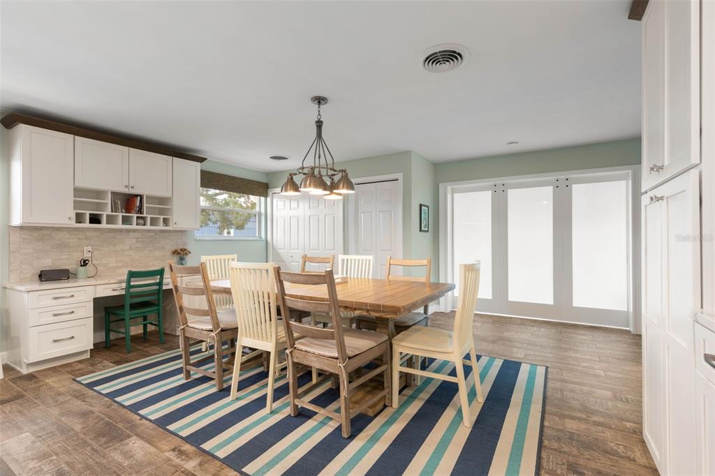 A dining room features a wooden table, striped rug, built-in desk, and white cabinetry — 76 BANYAN DRIVE, ORMOND BEACH, FL