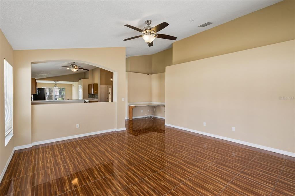 An empty room with wood-look tile flooring, a vaulted ceiling, and a built-in desk area — 1 CATALINA COURT, KISSIMMEE, FL